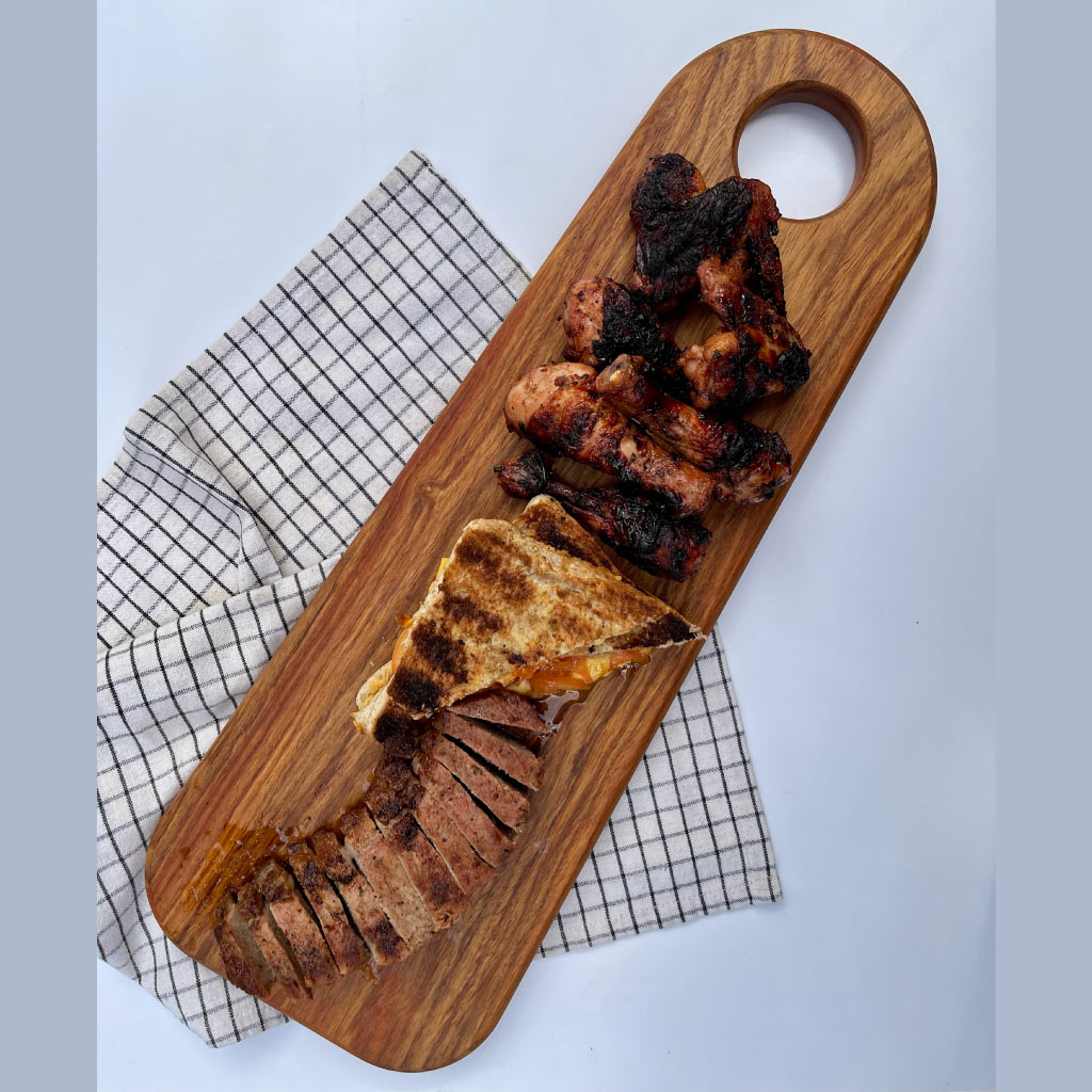top view of handcrafted kiaat long serving board with braai meat