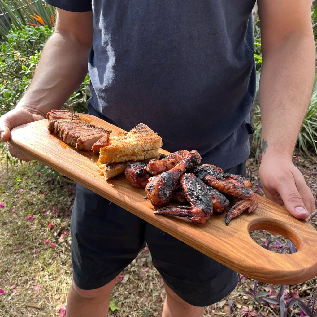 Side view of handcrafted kiaat long serving board with braai meat