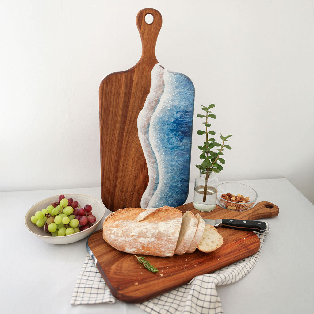 Handcrafted large paddle serving board showing ocean resin display side and kiaat wood chopping side with loaf of bread