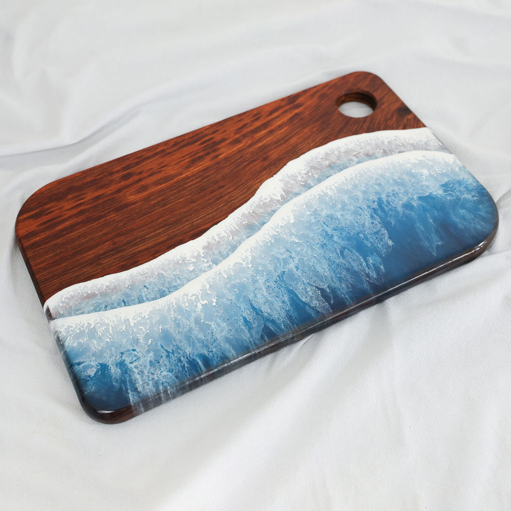 Angled view of handcrafted kiaat wood large rectangle serving board with blue ocean resin wave design