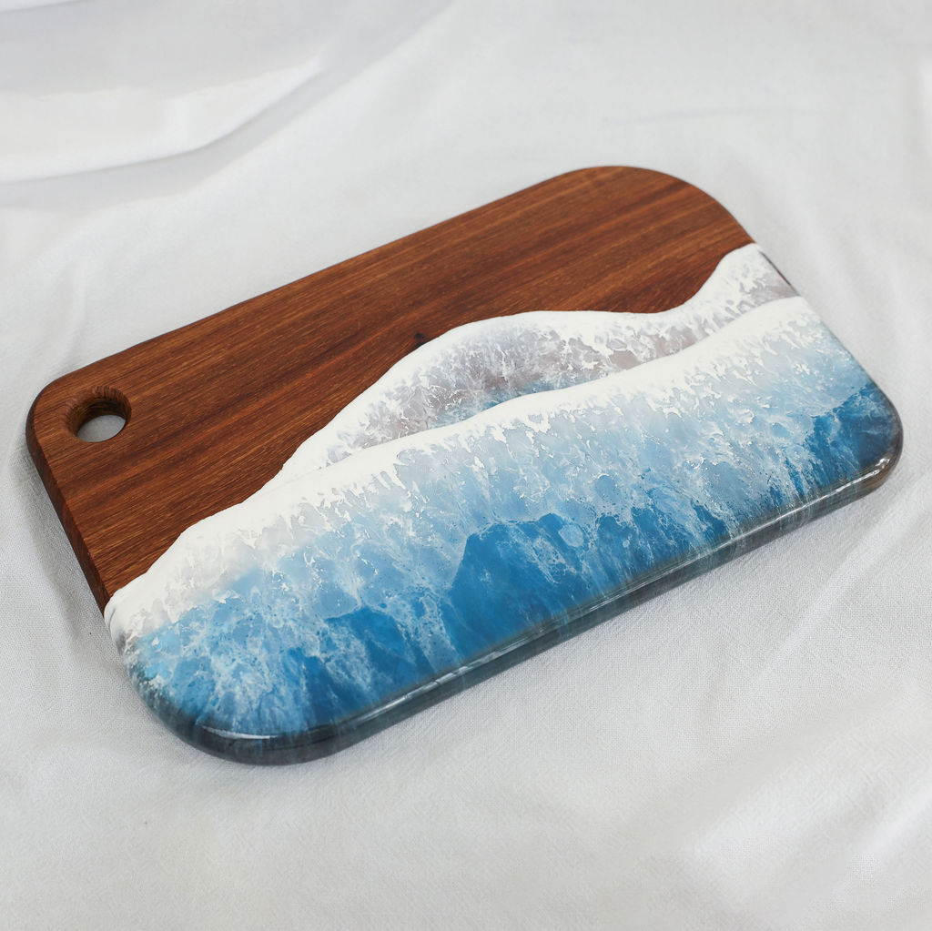 Angled view of handcrafted kiaat wood small rectangle serving board with blue ocean resin wave design