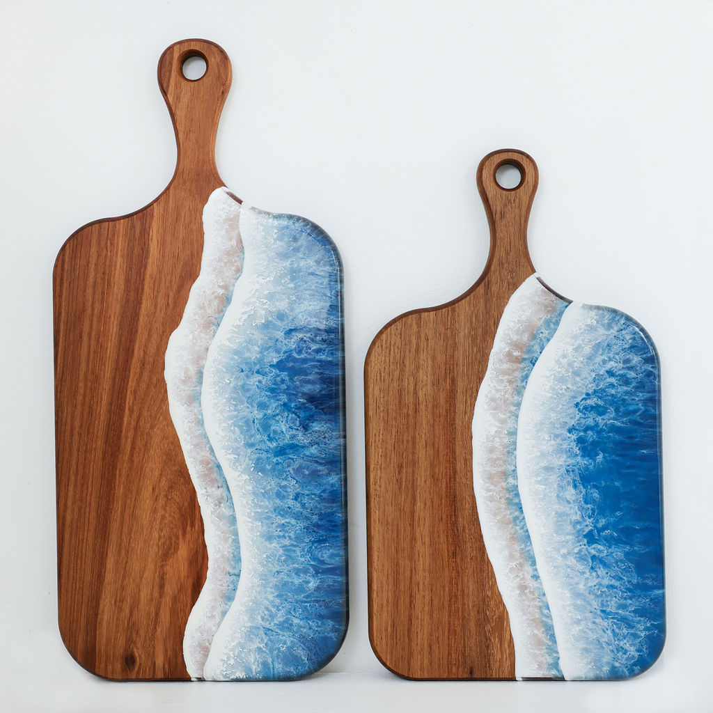 Handcrafted large and medium paddle serving boards with blue ocean resin wave design shown together to compare sizes