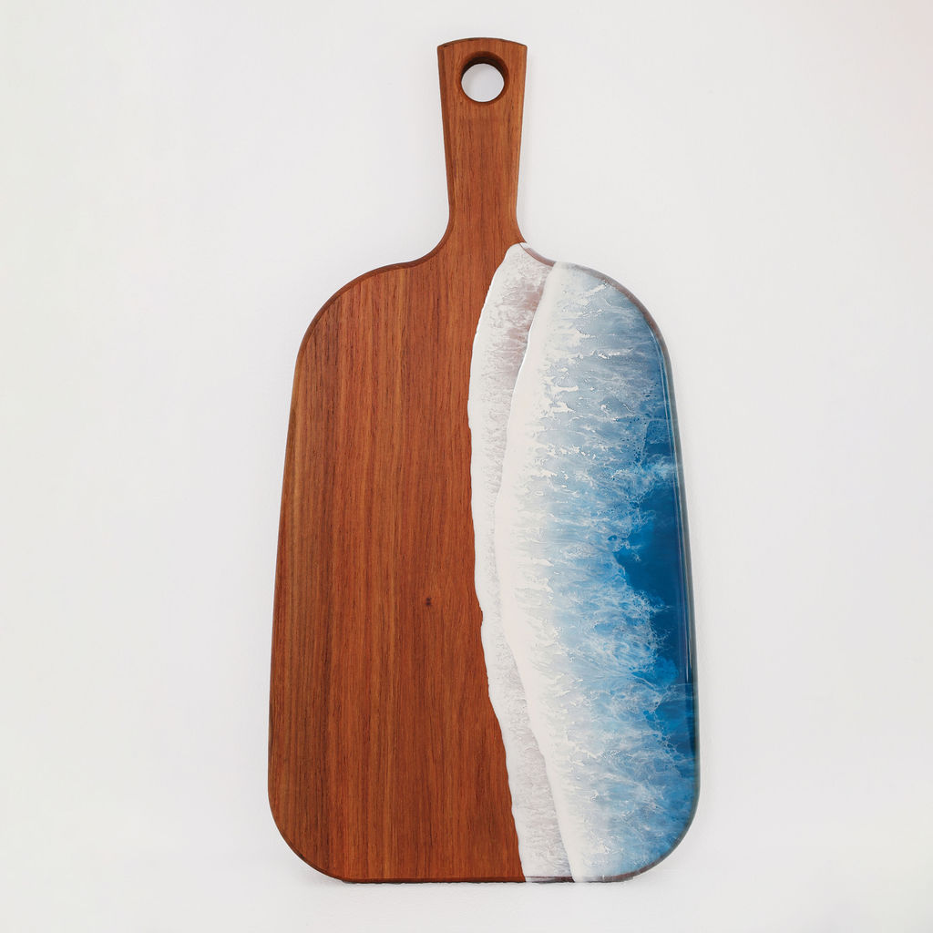Front view of handcrafted organic medium paddle serving board made from kiaat wood with blue ocean resin wave design
