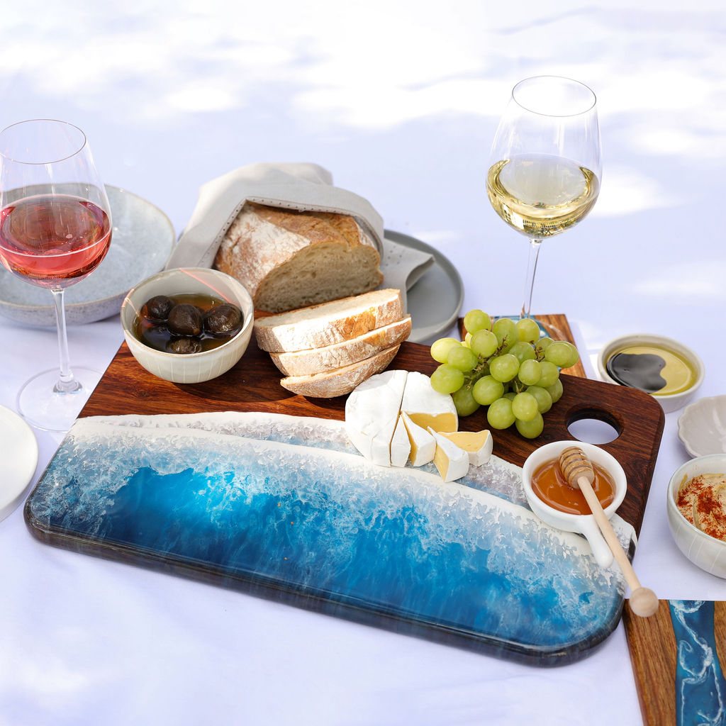 Handcrafted large rectangle serving board with ocean resin wave design styled with a variety of foods for entertaining