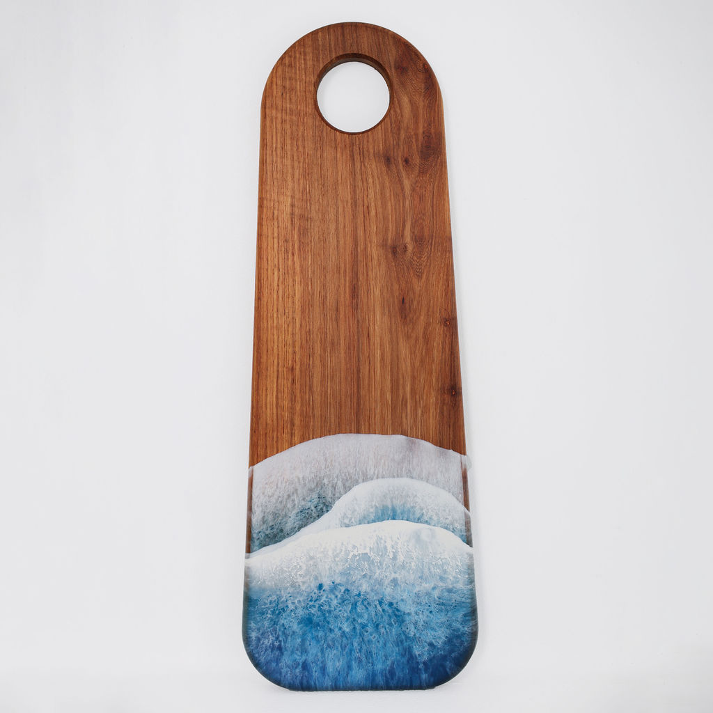 Front view of handcrafted long kiaat wood serving board with blue ocean resin wave design