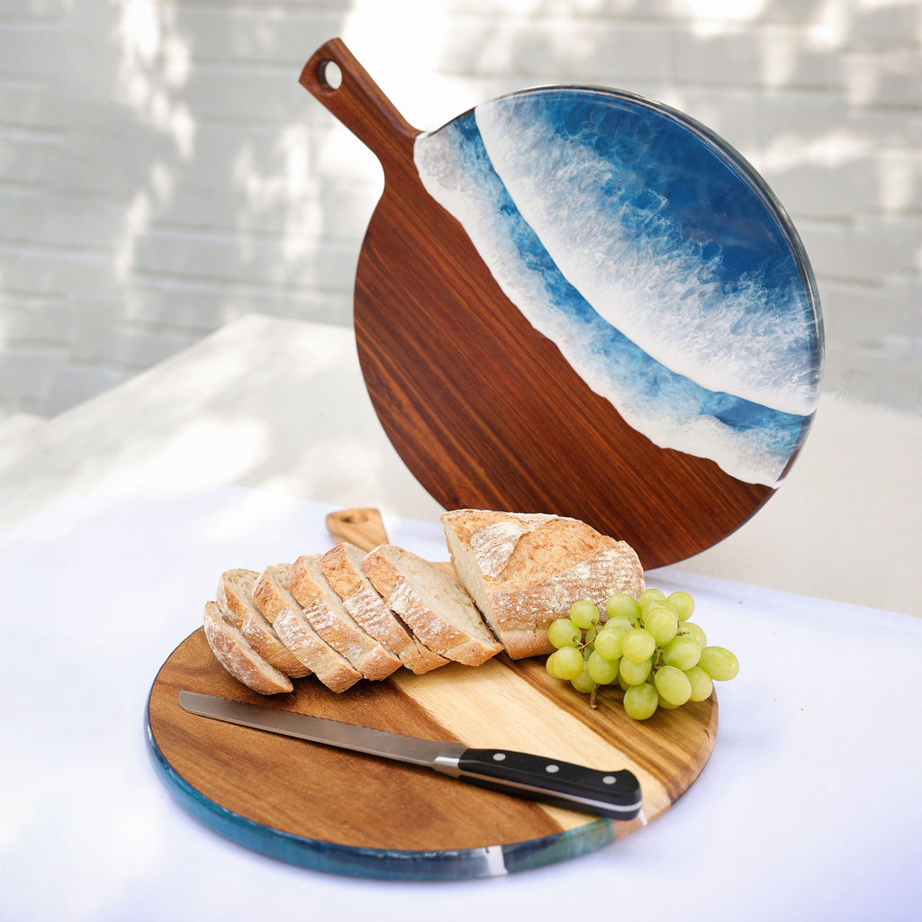 Handcrafted large paddle serving board showing ocean resin display side and kiaat wood chopping side with loaf of bread