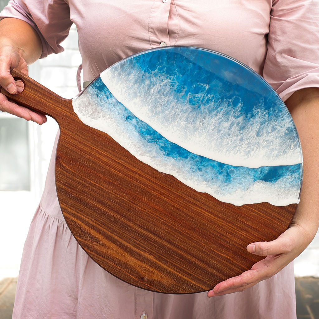 Founder holding a round paddle serving board with ocean resin wave design