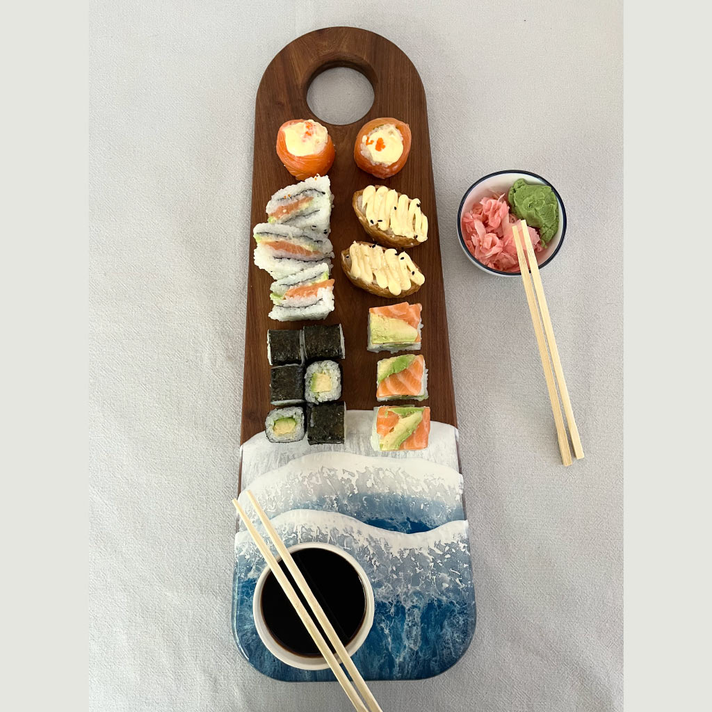 Handcrafted long serving board with ocean resin wave design, styled with sushi