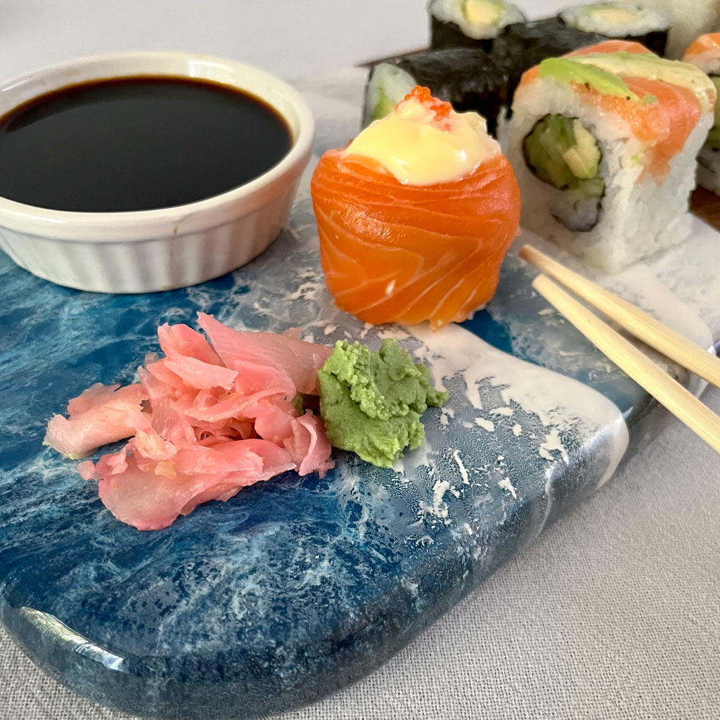 Handcrafted long serving board with ocean resin wave design, close up of board styled with sushi