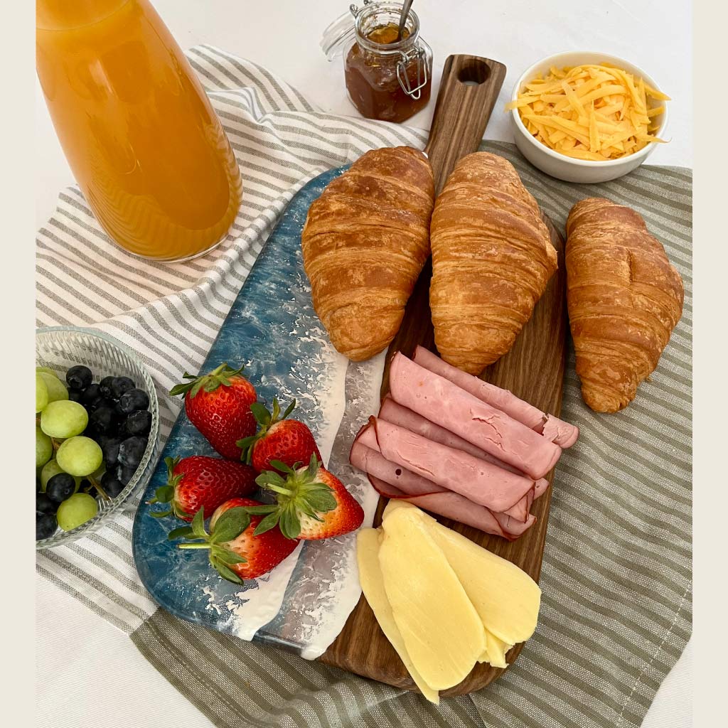 Handcrafted organic medium paddle serving board with ocean resin wave design styled with a variety of foods for entertaining