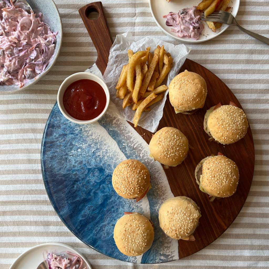 Handcrafted round paddle serving board with ocean resin design styled with a variety of foods for hosting and entertaining